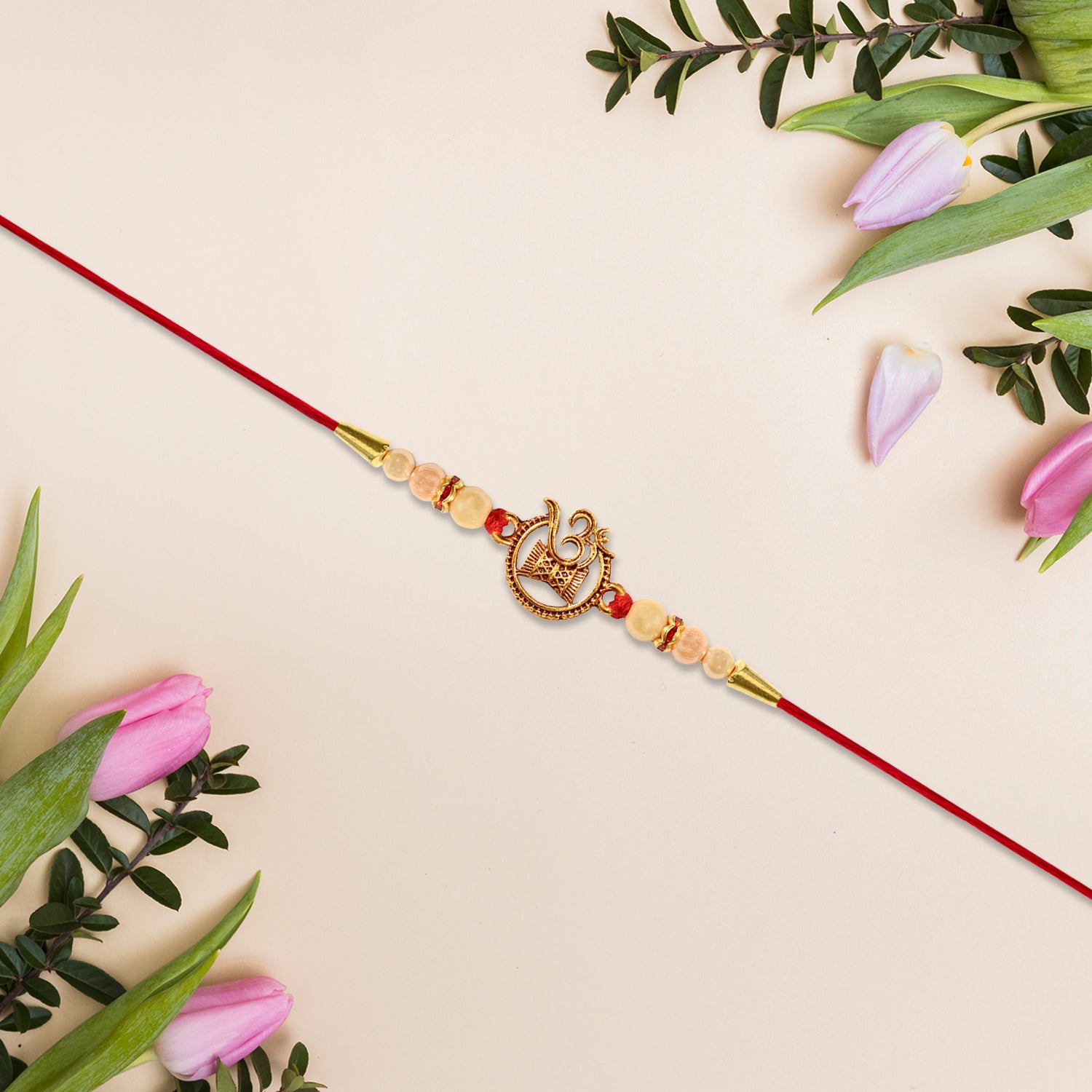 Designer Religious Rakhi With Golden Om And Swastik Motif And Pearl Beads On Red Thread
